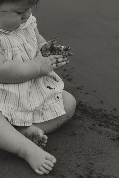 toddler playing in sand during lifestyle family photos in pei