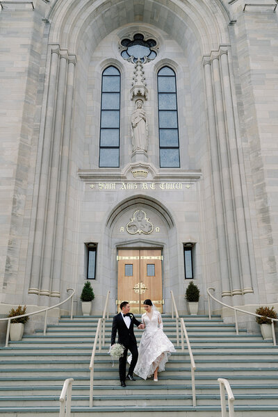 just married groom and bride coming down stairs of cathedral