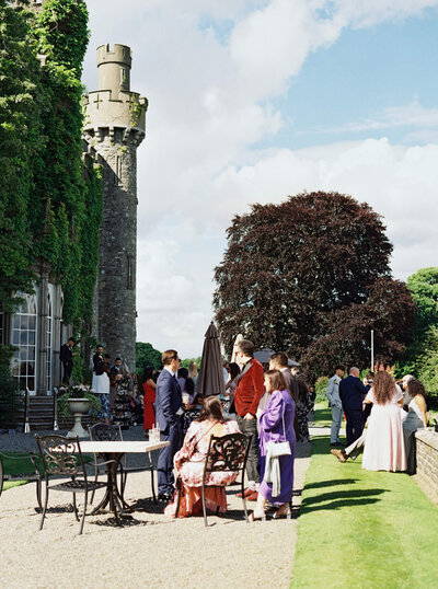 Candid film images of guests mingling during cocktail hour out on the patio at Luttrellstown Castle