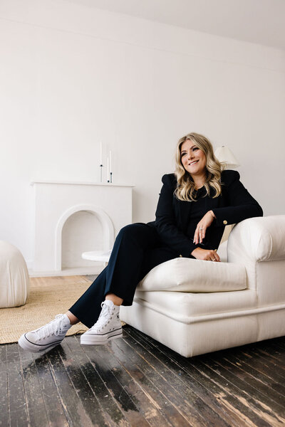 Calgary Realtor Leigh Kormos seated on an off-white couch