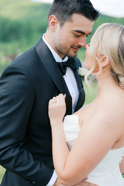 Black and white photo of bride pulling groom by his lapel towards her for a kiss