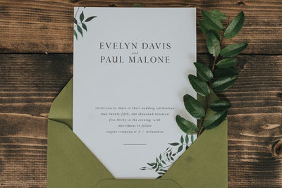 white invite with green foilage