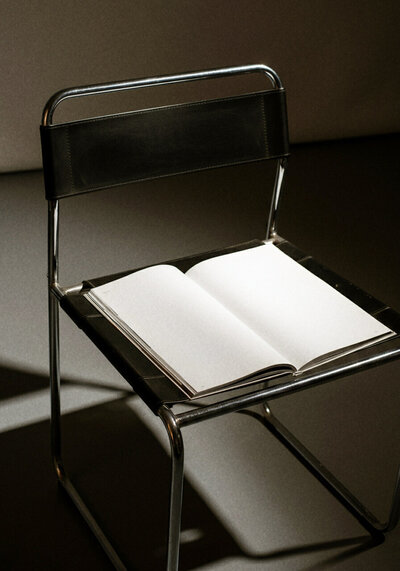 A modern chair with a white open notepad on it.  