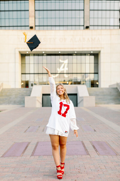 Grad tosses cap in the air in front of Bryant-Denny Stadium in Tuscaloosa