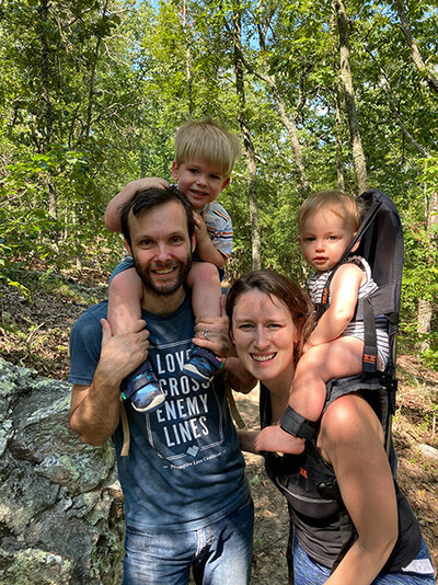 A man and woman walk on a trail with two children, enjoying a family outing in nature.