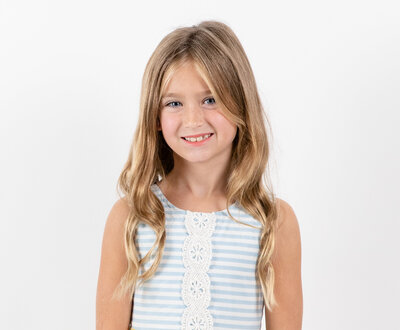 Young girl smiles for photo in blue and white striped tank top
