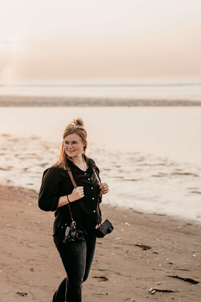 Fotograaf Tessa Baas op het strand met twee camera's 