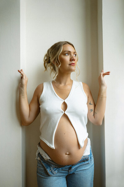 Expecting mother in a parking lot wearing white lingerie and a pearl mesh top.