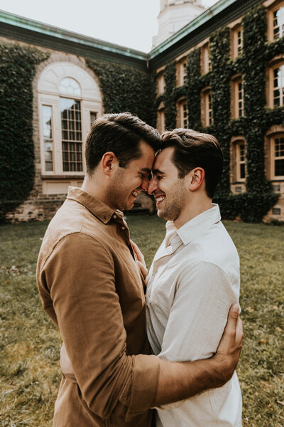 two men smiling and embracing with their foreheads touching