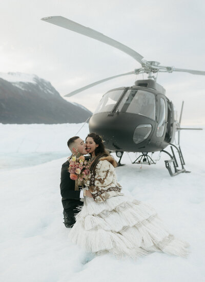 A man looking at a woman wearing a wedding dress on the beach at Salted Roots in Alaska.