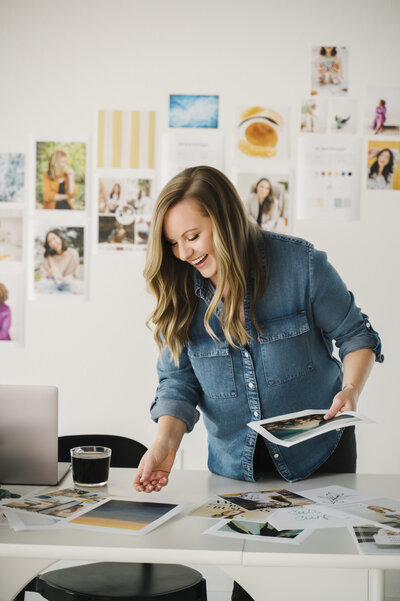 A photo of Krista Marie, a brand photographer and website designer, flipping through printed brand photos on her desk