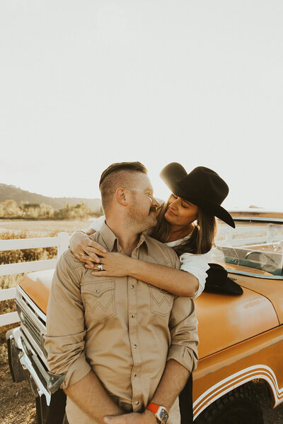 couples takes their western engagement photos wearing cow boy hats in front of his old ford truck