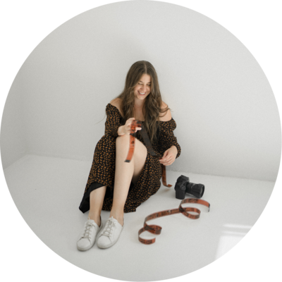 photo of a woman in a brown dress sitting on the ground looking at an unravelled roll of 35mm film