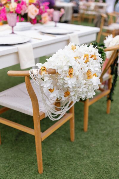 A white floral arrangement on the back of a chair 