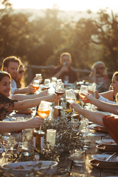 A table full of people at a wedding reception in Tuscany Italy, they are toasting to the bride and groom. 