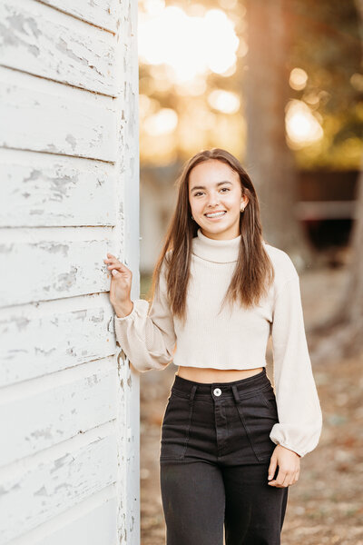 Little girl smiling at camera surrounded by fall scenery.