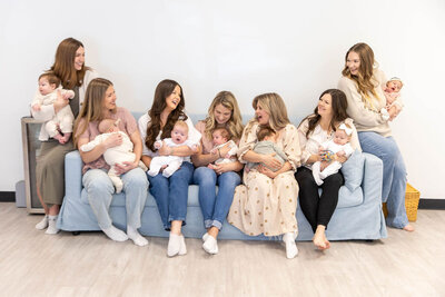 Group of women holding their babies while sitting on a couch