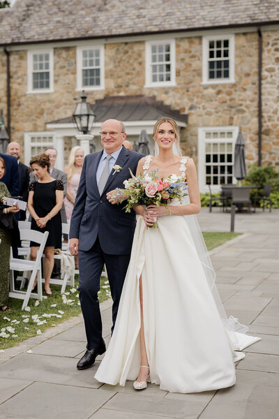 Bride walking with bouquet alongside a man