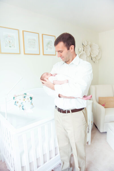 Dad holds baby in white nursery
