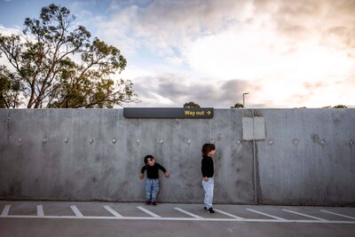 To brothers playing in a roof top carpark with epic clouds behind them