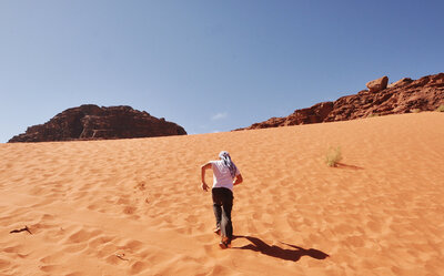 Man running up a sand dune in Jordan