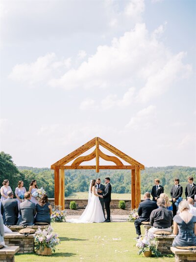Couple being married under arbor surrounded by flowers