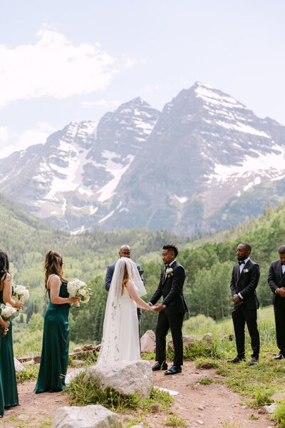 Wedding ceremony at Maroon Bells with couple exchanging vows against the alpine mountain backdrop