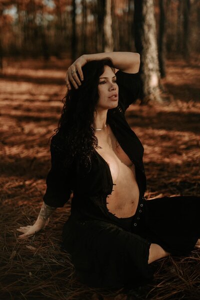 Moody maternity portrait in Naval Oaks Gulf Breeze Florida pregnant woman sitting outdoors, cinematic editorial film style