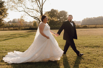 Bride and Groom walking together hand in hand through a field