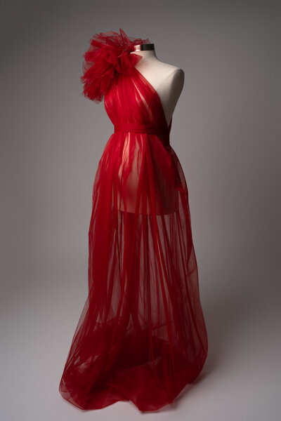 Red maternity gown with tulle overlay and bold shoulder detail