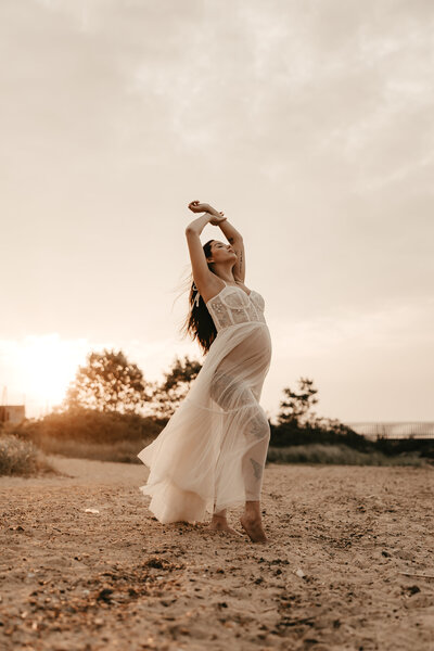 Expecting mother in earth-toned dress holding baby bump during soft, natural light maternity photography session – Mendham, NJ