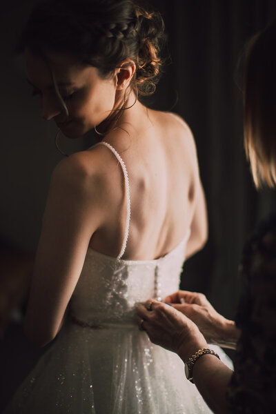 Bride gets buttoned into her gown