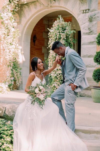 Two merriers laugh while one kisses the hand of the other at a Cairnwood Estate wedding
