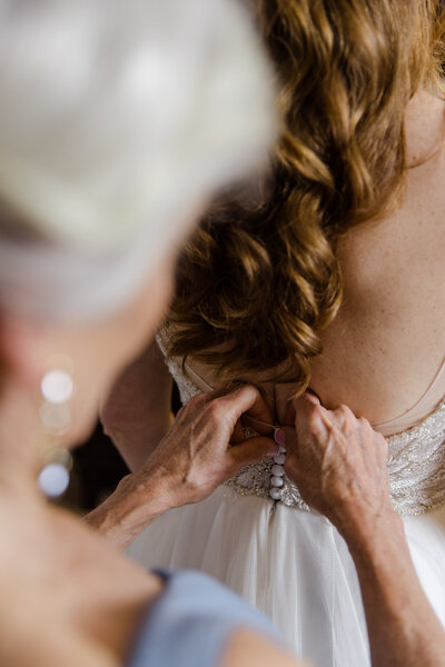 mother of bride buttons up bride dress for photos on NJ wedding day