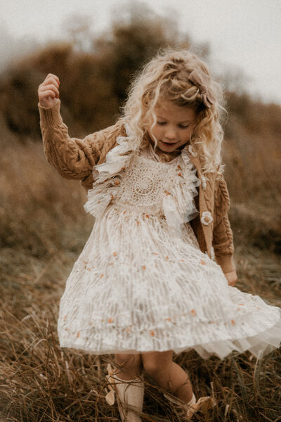 Photo of a little girl twirling her dress in a field.