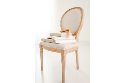 A stack of linen photo albums and matted frames displayed on a neutral wooden chair — Portrait photography in Raleigh.