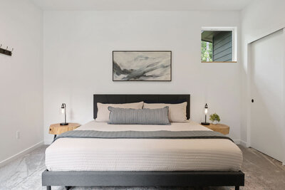 Bedroom with a black bed, neutral bedding, and wall art