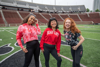 three models wearing college game day gear on the football field