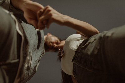 Photo of a couple holding hands and nuzzling faces together, viewed from below.