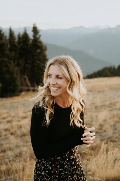 amy galbraith, an elopement photographer in washington, sits and giggles with her family in the back of her ford transit camper van