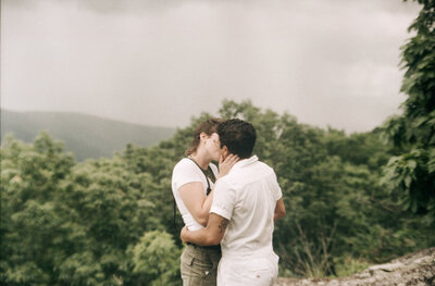 Bride and groom standing hand in hand with a mountain lake behind them during their intimate Virginia elopement, photographed in natural light and soft tones.

