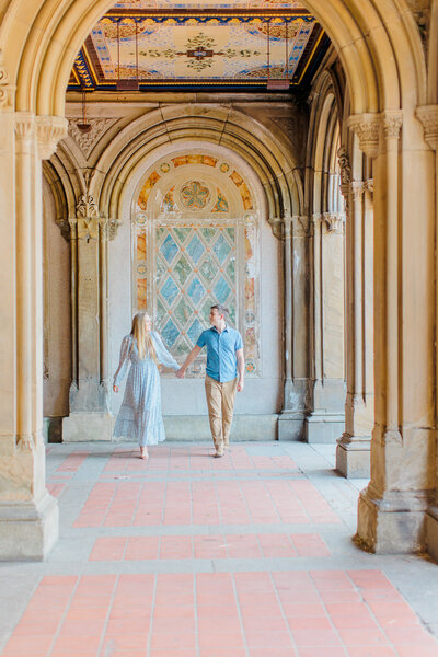 Couple holding hands for an engagement photo in an ornate hall