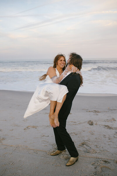 A bride and groom embrace on a picturesque beach, capturing a moment of love and joy against the ocean backdrop.