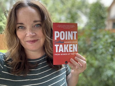smiling woman holding up a book called Point Taken