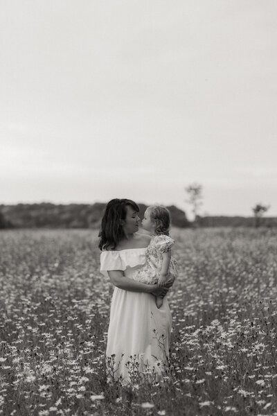 woman holding daughter in grass field