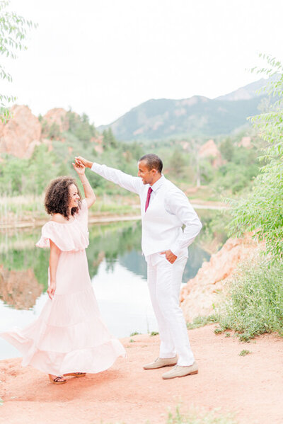 couple at red rocks open space where the groom is twirling the bride as she holds onto her pink dress as she twirls and it spins out