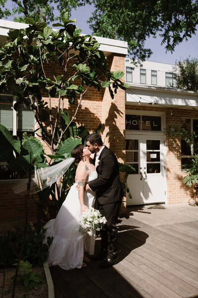 Bride and. groom kissing outside carpenter hotel wedding in Austin