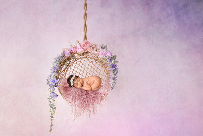 Infant baby sleeping in floral hoop swing. Captured by H&N Photography Denver