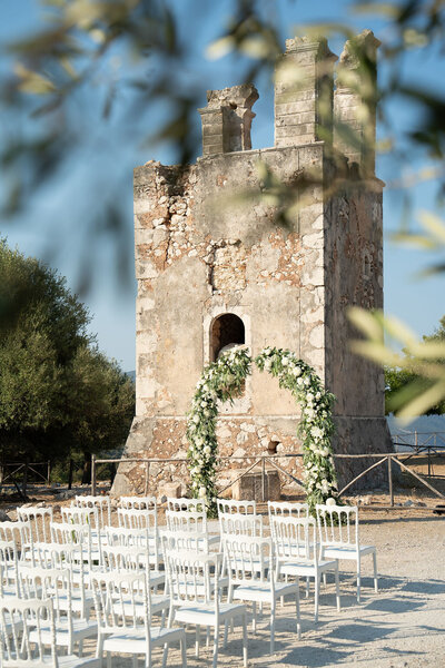 Outdoor wedding ceremony beside a historic chapel in Greece, designed by a destination wedding planner with refined, romantic style.