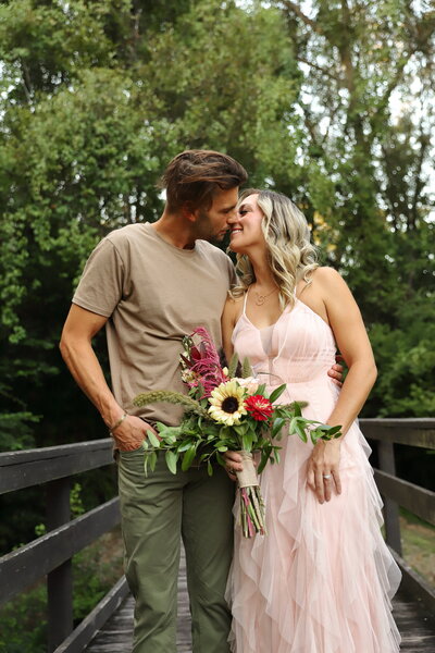 Couple kissing during their anniversary session with spring flowers at golden hour